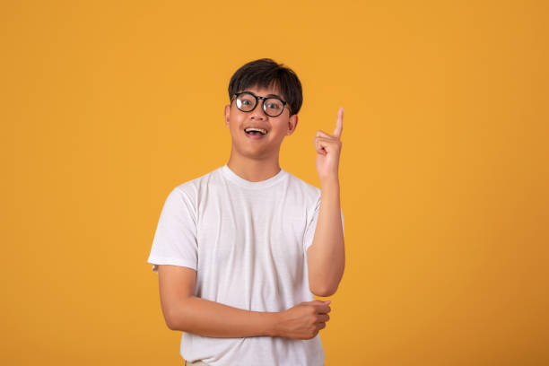 istock Young Asian man standing on orange background, pointing his finger. Looking at camera. 1317075895