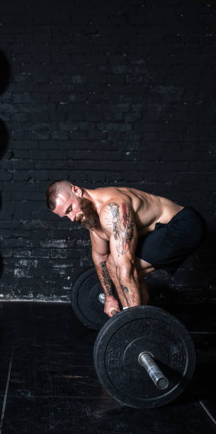 istock Young active strong fit muscular sweaty man with big muscles doing barbell weight dead lifting hardcore cross training workout in the gym dark image real people exercising 1317076841