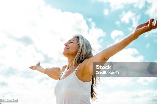 Joyful Senior Woman Enjoying Freedom Standing With Open Arms And A Happy Smile Looking Up Towards The Sky People And Happiness Concept Stock Photo - Download Image Now