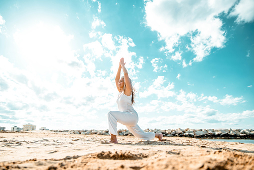 Senior woman doing yoga exercise at beach - Calm and meditation concept