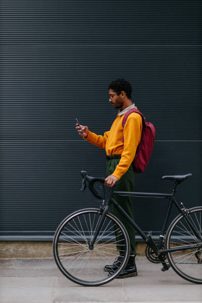 istock Trendy handsome cyclist on city street using phone 1317079809