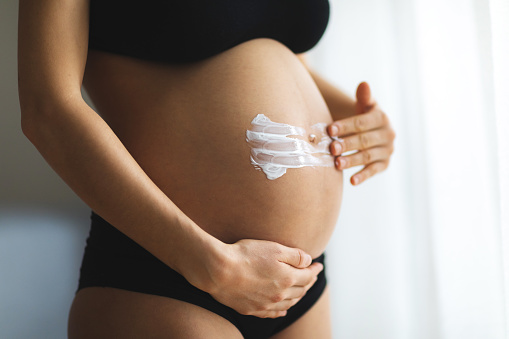 Mujeres embarazadas poniendo crema anti elástica en su vientre. photo