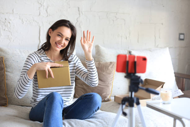 istock Young beautiful female blogger recording video while unpacking parcel at home. 1317080616