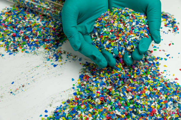 Crushed plastic on green gloved hand. Reuse of plastic. polymer beads. Scraps obtained from plastic waste. The world's plastic reduction policy. Scraps plastic on white background.