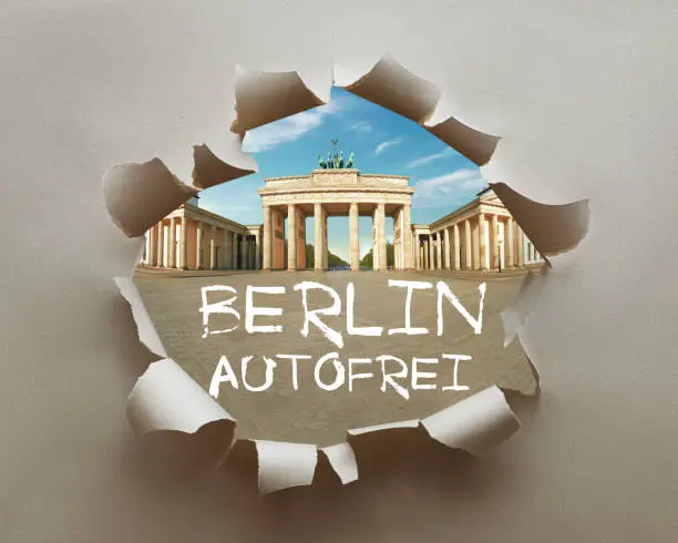 Berlin autofrei, or car free Berlin in German language. Berlin activists push initiatiev for a car-free Germany. Brandenburg Gate in craft paper hole with text.