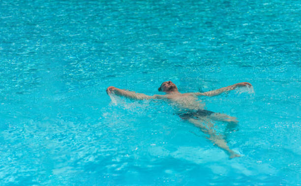 istock a man swims on his back in the pool on a sunny day in summer 1317081725
