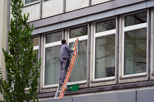 Window cleaner on leader at City of Zurich cleaning windows of office building. Photo taken May 7th, 2021, Zurich, Switzerland.
