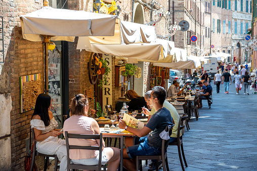 Florence, Tuscany-Italy - 08/24/2020: A restaurant in a pedestrian street with small canopies in Italy, where tourists and passers-by eat and walk by.