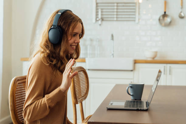 istock Girl using laptop with headphones and waving hand 1317092098