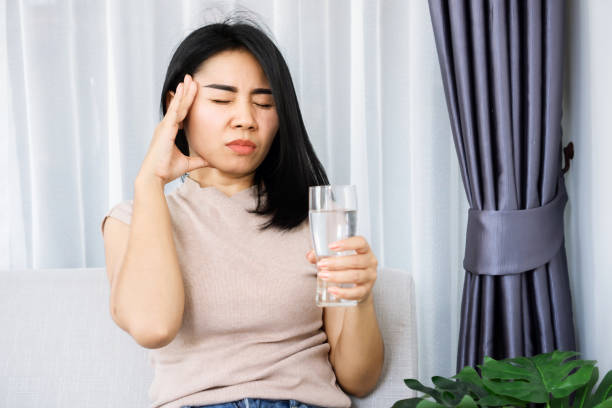 istock Asian woman suffering from headache after drinking cold water hand holding her head 1317093104