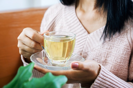 woman hand holding glass of hot, warm tea, closeup woman hand drinking tea relaxing time