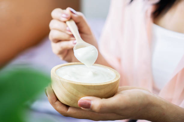 mujer a mano comiendo yogur a mano sosteniendo cuchara de madera y tazón de yogures - yogur fotografías e imágenes de stock