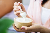 woman hand eating yogurt hand holding wooden spoon and bowl of yogurts