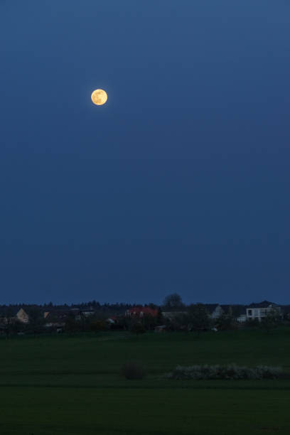 istock Full moon over rural landscape at blue hour outside village 1317093201