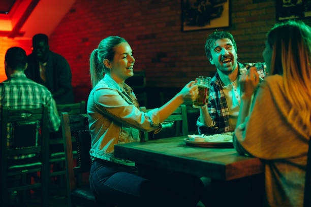 istock Cheerful young adults drinking beer and toasting while having fun in a bar at night. 1317094523