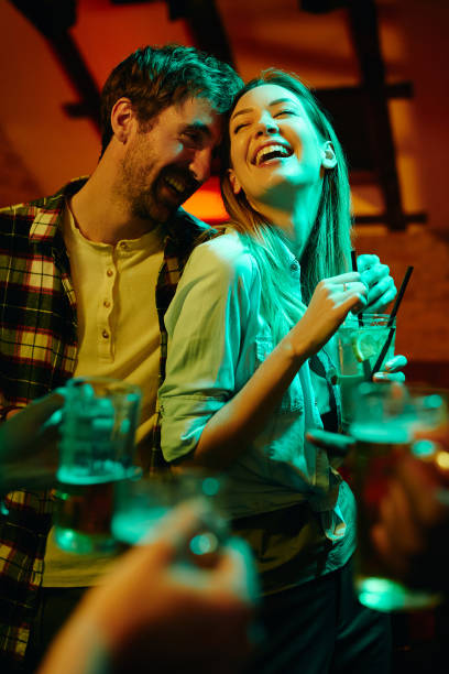 istock Young happy couple laughing while drinking and having fun in a pub at night. 1317094537