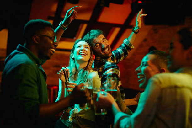 istock Group of cheerful friends drinking and dancing while gathering in pub at night. 1317095042