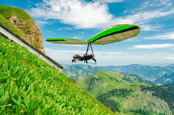 Hang glider pilots flies from steep slope high in the mountains. Diedamskopf, Austria. Extreme airborne sport.