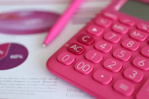 Photo of Pink calculator and pen lying on documents with graphs and diagrams closeup