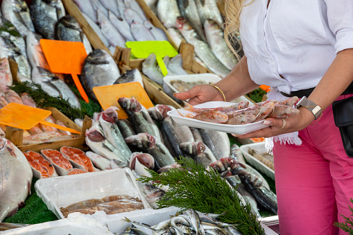 An elderly woman shopping at the fish market.