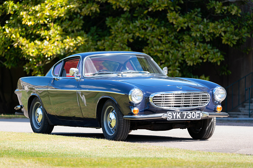Hertfordshire, UK - May 7, 2021: The sun shines down on a dark blue Volvo 1800S from 1967. The car was made famous in the sixties when Roger Moore drove a white example in the tv show \