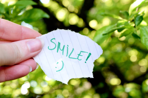 istock Human hand holding paper with smile text in nature 1317113631