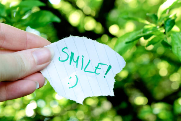 istock Human hand holding paper with smile text in nature 1317114045