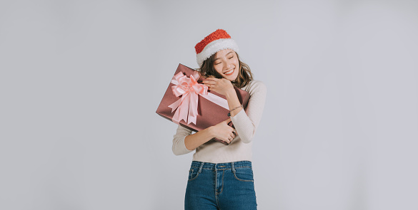 young asian chinese female with santa hat in studio gray background