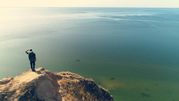 gotland sverige july  9 - 2014  - unknown young man looking out over the sea from a cliff on the Swedish island of Gotland which is quite close to Stockholm city by the Baltic Sea,
