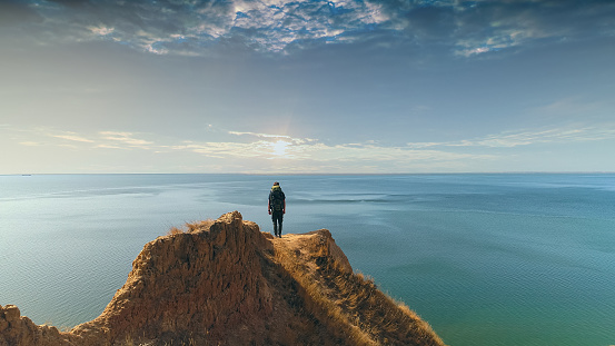The hiker standing on a mountain against the sea sunset background