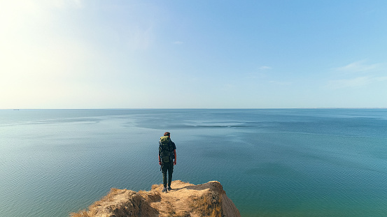 The hiker standing on a mountain on the beautiful sea view background