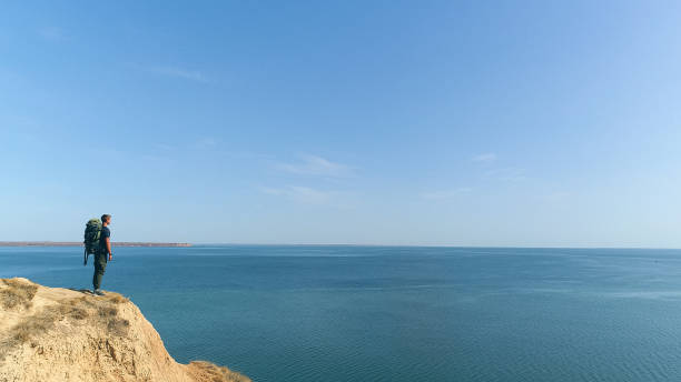 istock The man with a backpack standing on a mountain on the sea background 1317116653