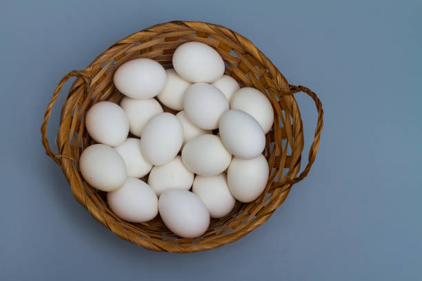 istock Basket with white chicken eggs on a gray background 1317117055