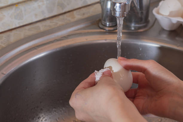 istock A man washes chicken white eggs under a tap with soda water to remove dirt and germs 1317117070