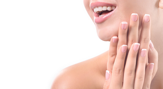 Closeup portrait of a happily smiling girl with french manicure on a white background. Copy space.