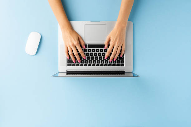 istock Overhead shot of woman’s hands using laptop on blue table. Office desktop. Flat lay 1317122848