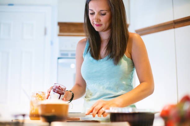 istock Millennial Female in Kitchen Preparing Meal Using Plastic Containers Photo Series 1317129610