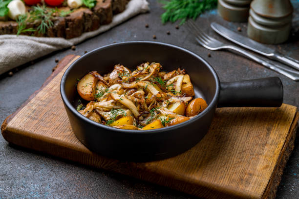 Fried potatoes with mushrooms on black frying pan on dark concrete table Fried potatoes with mushrooms on black frying pan on dark concrete table fried potato stock pictures, royalty-free photos & images