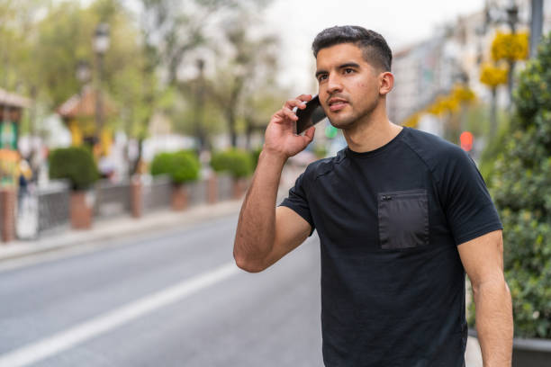 Young hispanic man with a dark complexion talking with the smartphone stock photo