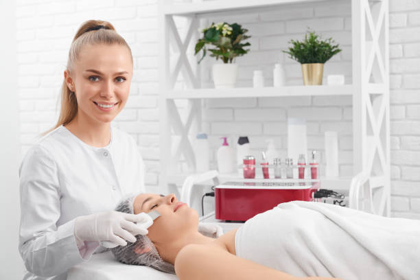 Smiling beautician doing beauty procedure for patient. stock photo