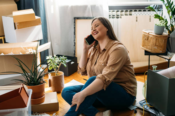 istock Moving In: Beautiful Happy Plus Size Woman Sitting on the Floor while Using a Smartphone 1317133412