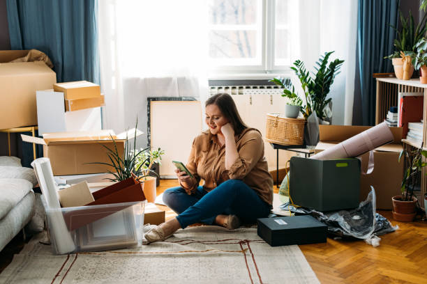 istock Moving In: Beautiful Happy Plus Size Woman Sitting on the Floor while Using a Smartphone 1317133416