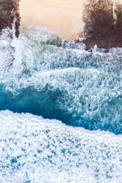 istock Ocean waves hitting a rocky beach. View from above. 1317134900