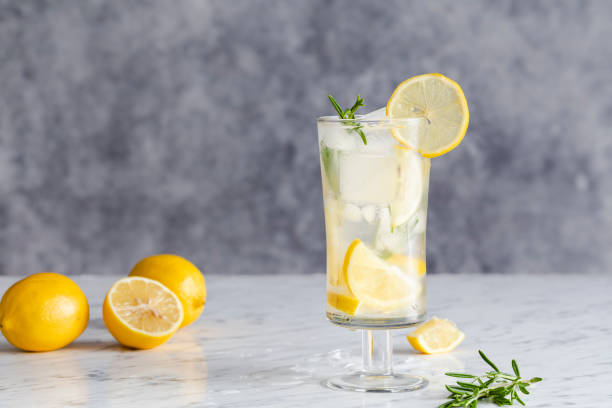 Lemon rosemary cocktail with ice. Lemon drink with rosemary and ice. Concept gin and tonic, GT.  Refreshing cocktail or detox mocktail with homegrown herbs. Copy space room for text. On a marble surface with gray background. Gin stock pictures, royalty-free photos & images