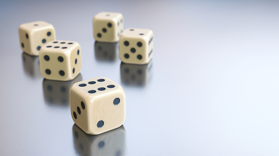 Extreme close-up on a few shiny ivory gambling dice on a white metallic surface with copy space