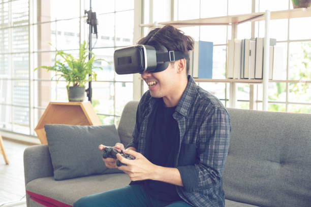 istock Happy young man with virtual reality headset or 3d glasses with controller gamepad playing video game at home. 1317139276