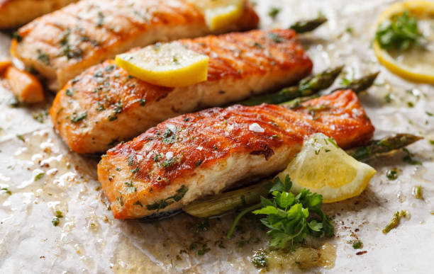 Baked salmon with aromatic herbs and lemon fruit on baking paper Baked salmon fillet with aromatic herbs and lemon on baking paper close up view filleted stock pictures, royalty-free photos & images