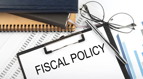 Text FISCAL POLICY on Office desk table with notebooks, supplies,analysis chart, on the white background. Top view stock photo