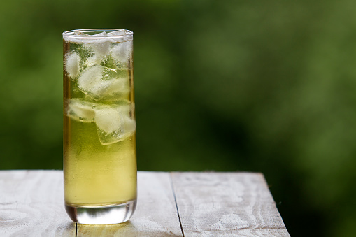 Green in a tall glass with ice on rustic table tea and focus background