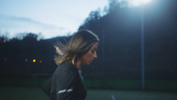 istock Young woman soccer player training on grass field at night. 1317142750